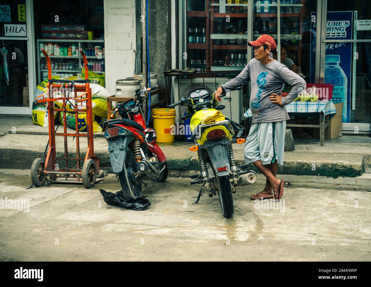 A pedestrian waiting near his motorcycle outside a corner store in El
