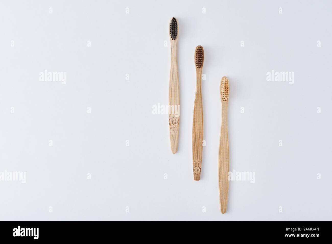 three wooden bamboo toothbrushes on white background, top view. Dental ...