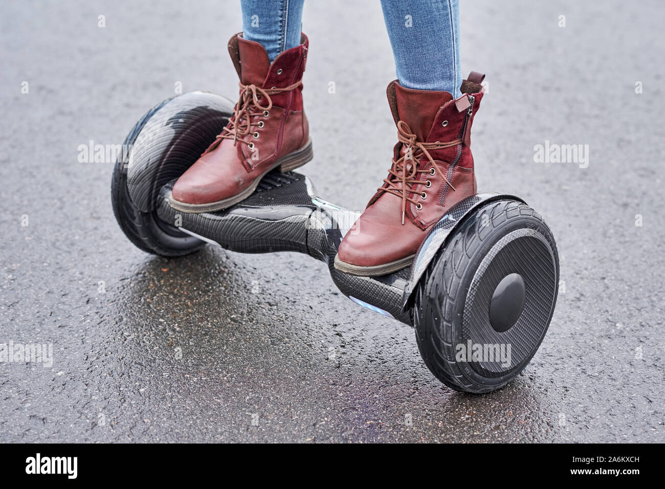 Woman using hoverboard on asphalt road, close up. Feet on electrical scooter outdoor Stock Photo