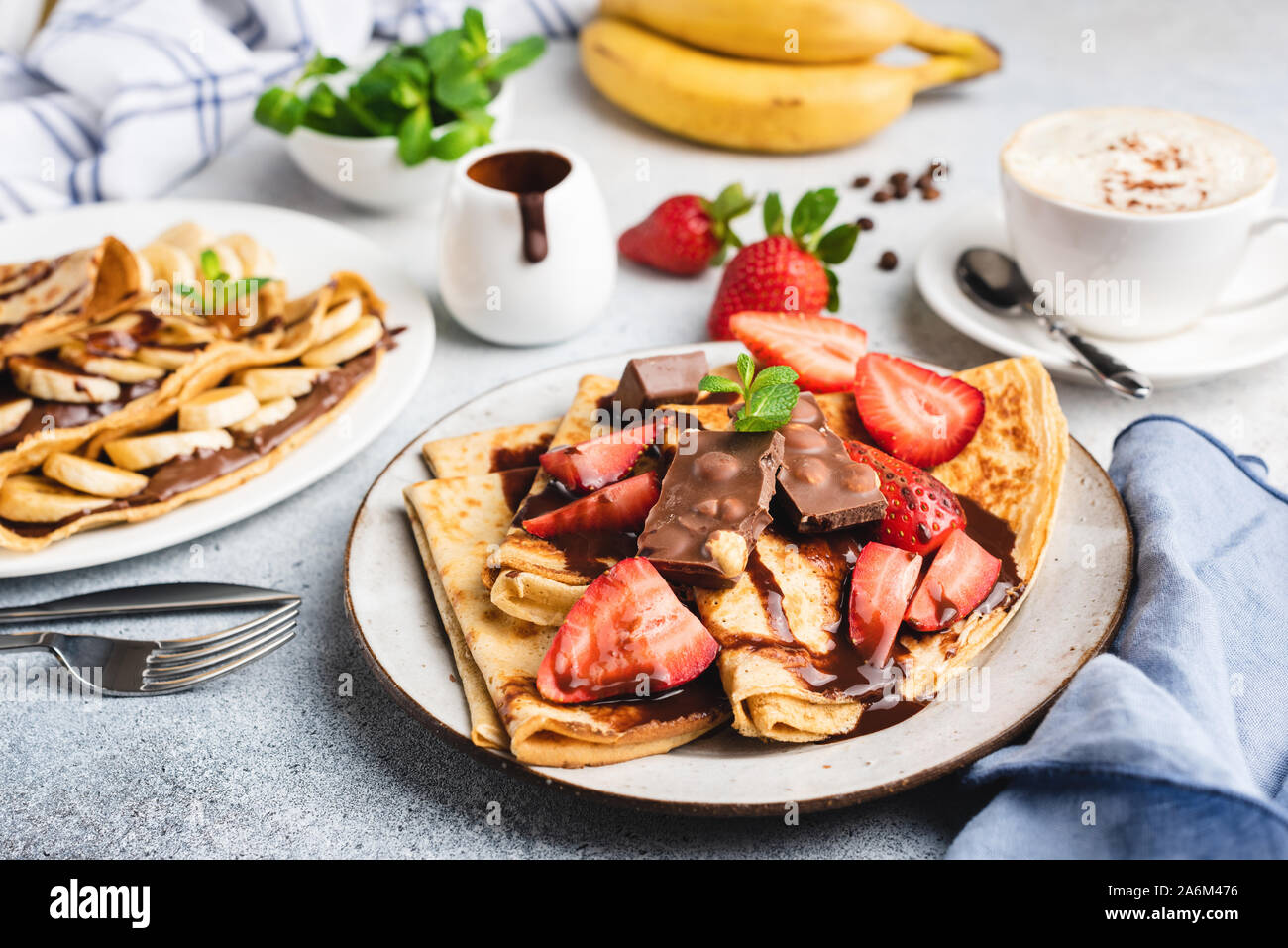 Crepes with chocolate, strawberry and banana. Tasty sweet food, dessert served in restaurant. Blini with chocolate syrup and fruits Stock Photo