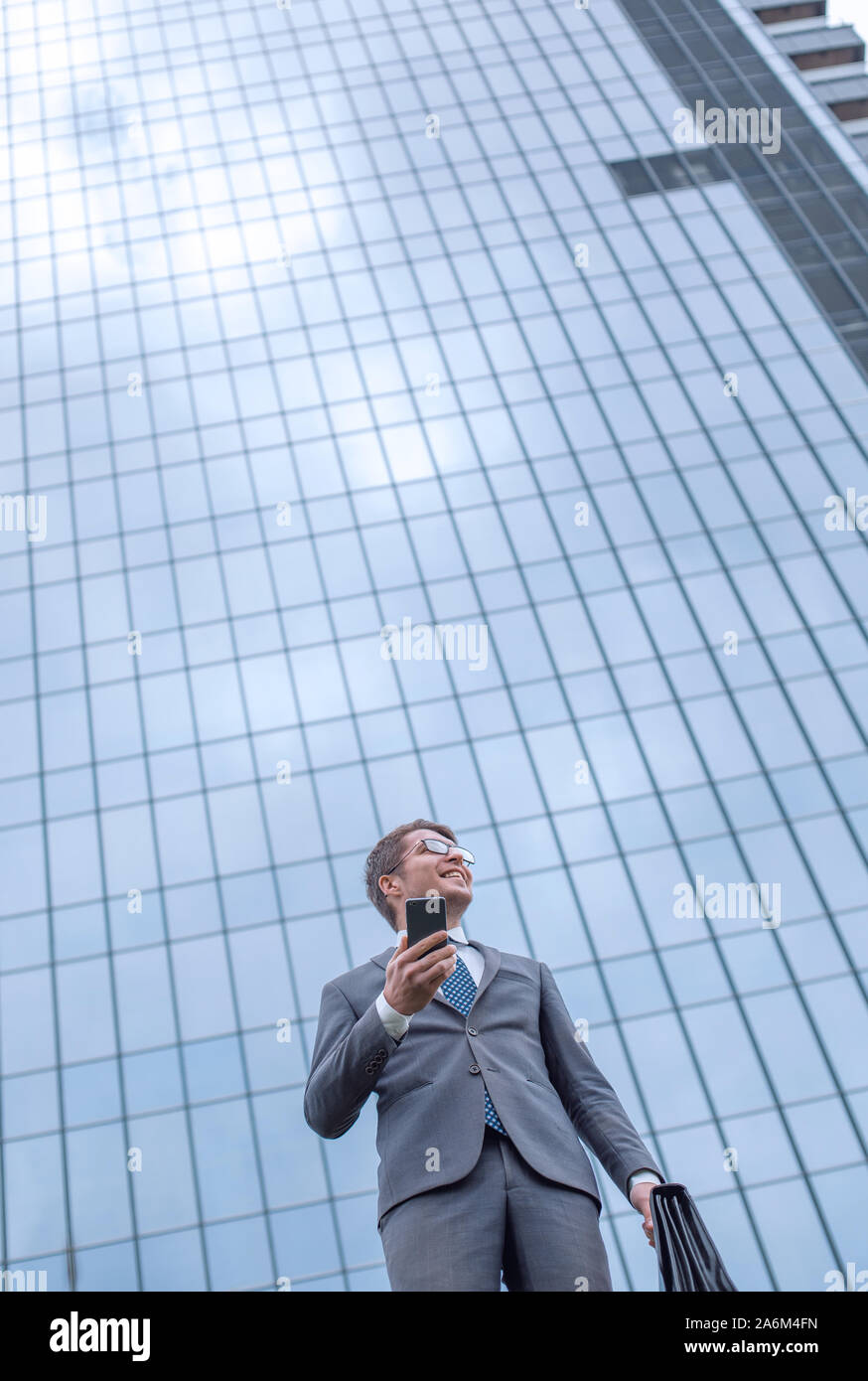 happy business man with smartphone standing near office building Stock ...
