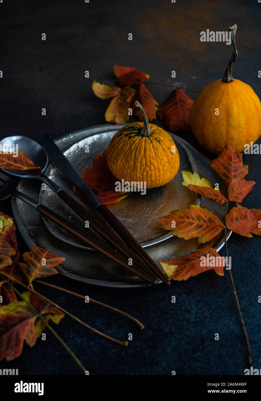 Autumnal table setting with bright yellow leaves and pumpkins on stone ...