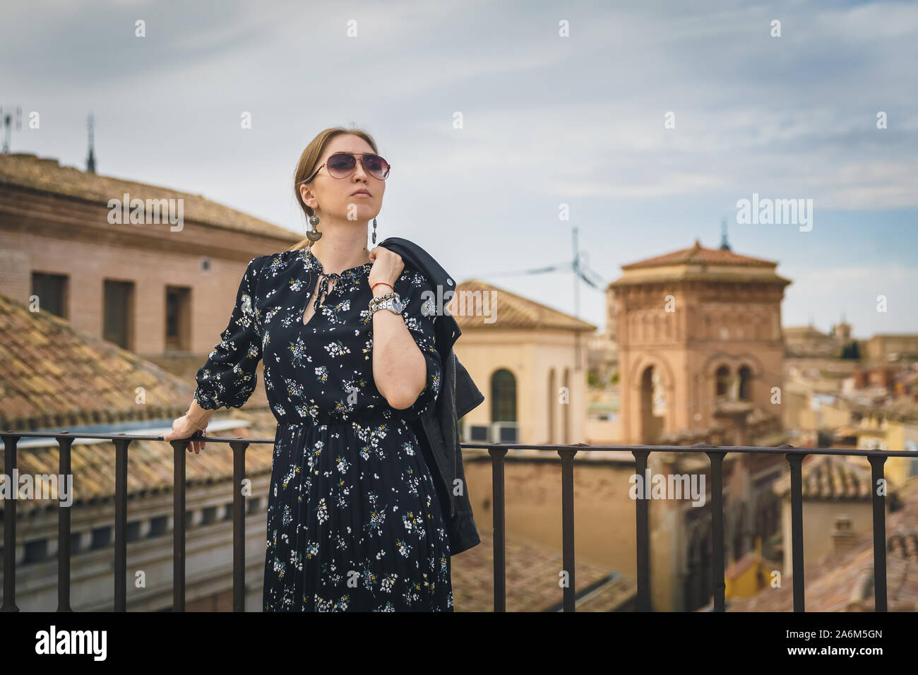 Stylish woman posing in the old part of the town against tile roofs. Medieval city of Toledo in the center of Spain. Stock Photo
