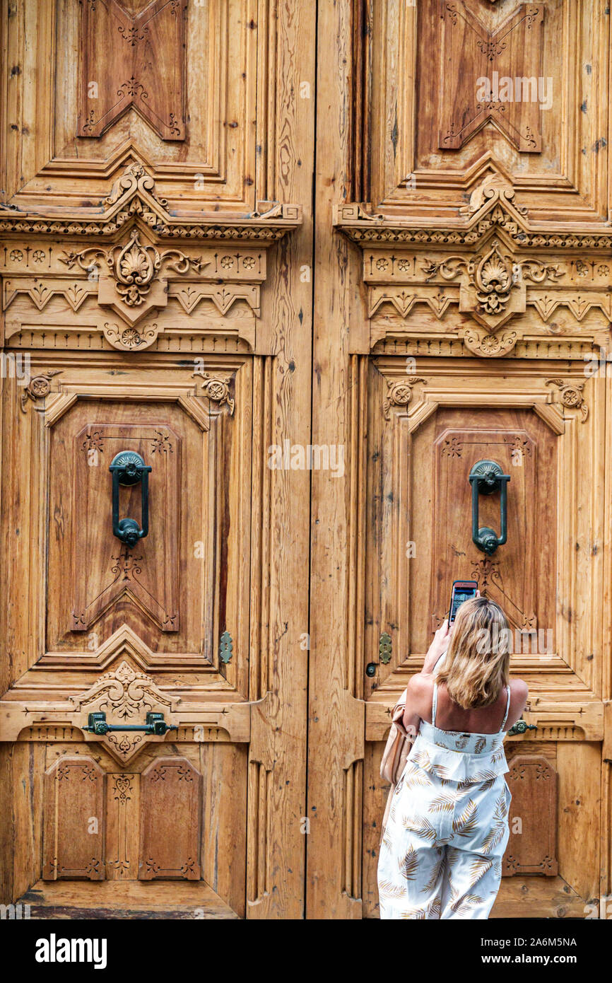 Valencia Spain,Ciutat Vella,old city,historic center,Calle de la Paz,ornate carved wood door,knockers,woman,taking photo smartphone,ES190829148 Stock Photo