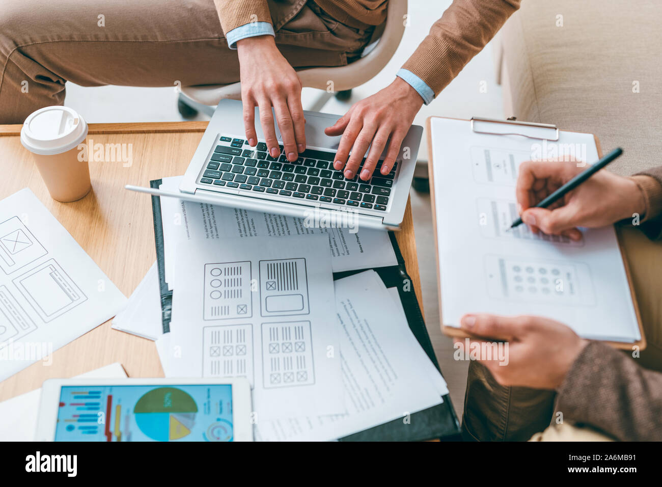 Software developer typing while his colleague making sketches of ...