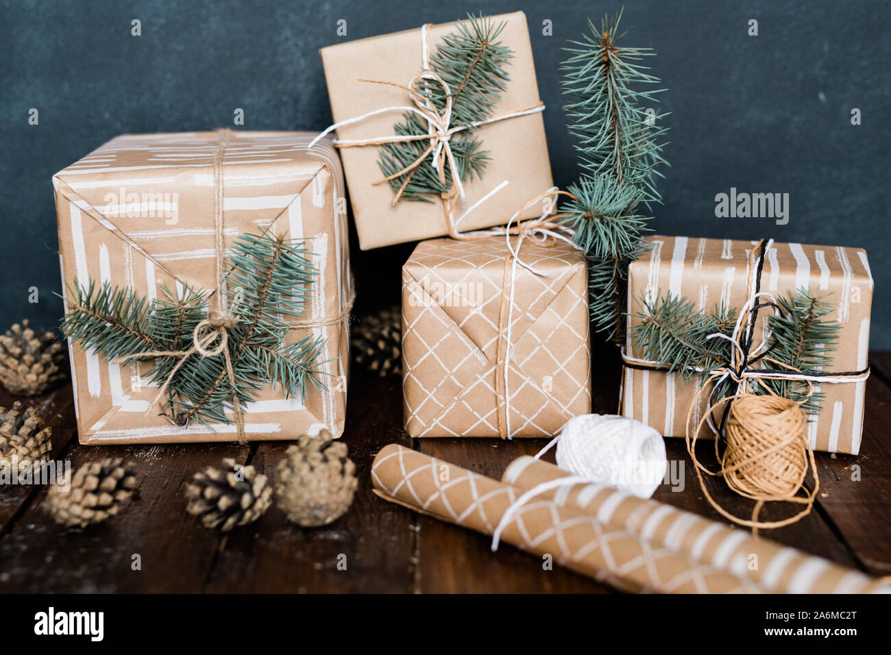 Giftboxes with conifer on top, rolled paper, threads for binding and pinecones Stock Photo