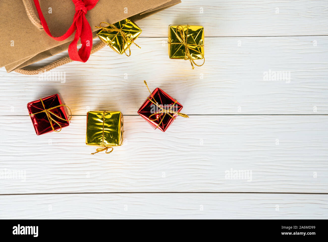 Christmas presents on a wooden table popping out of a paper bag. Copy space. Stock Photo