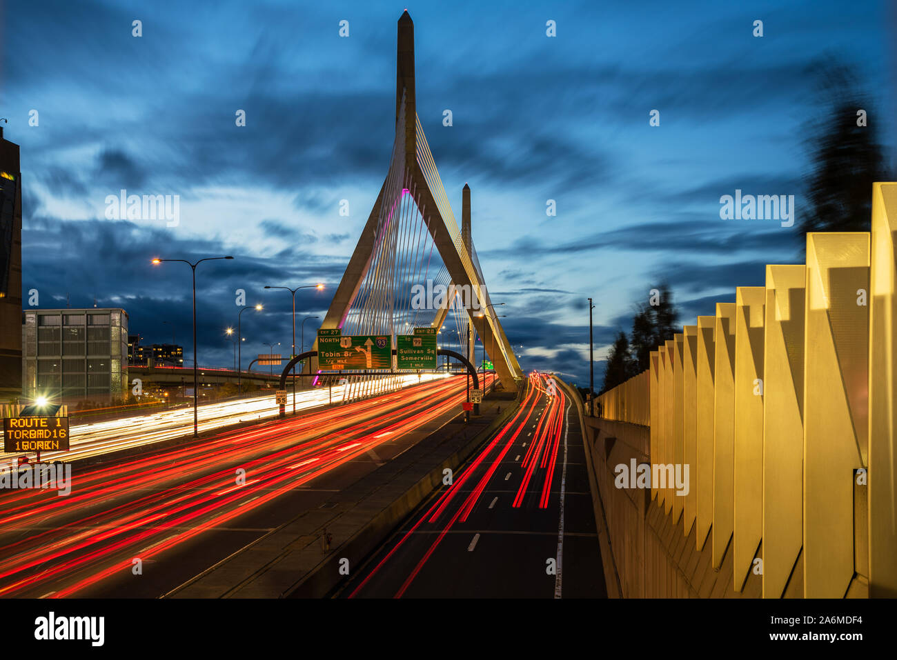 Highway suspension bridge with light trails left by passing vehicles at dusk Stock Photo