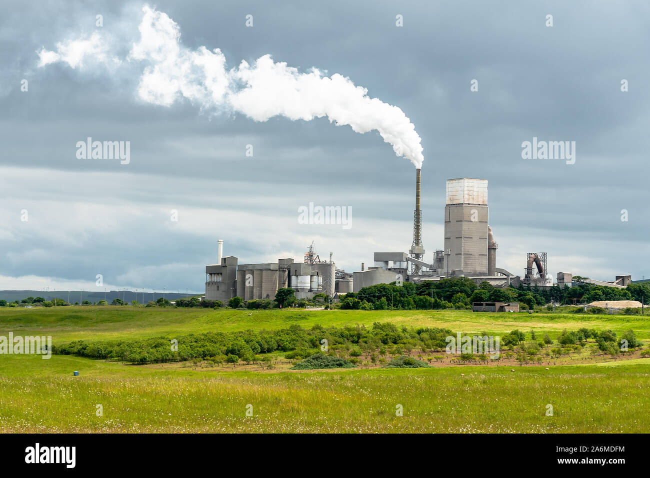 Cement factory in the Scottish countryside under a stormy sky. Concept of pollution. Stock Photo