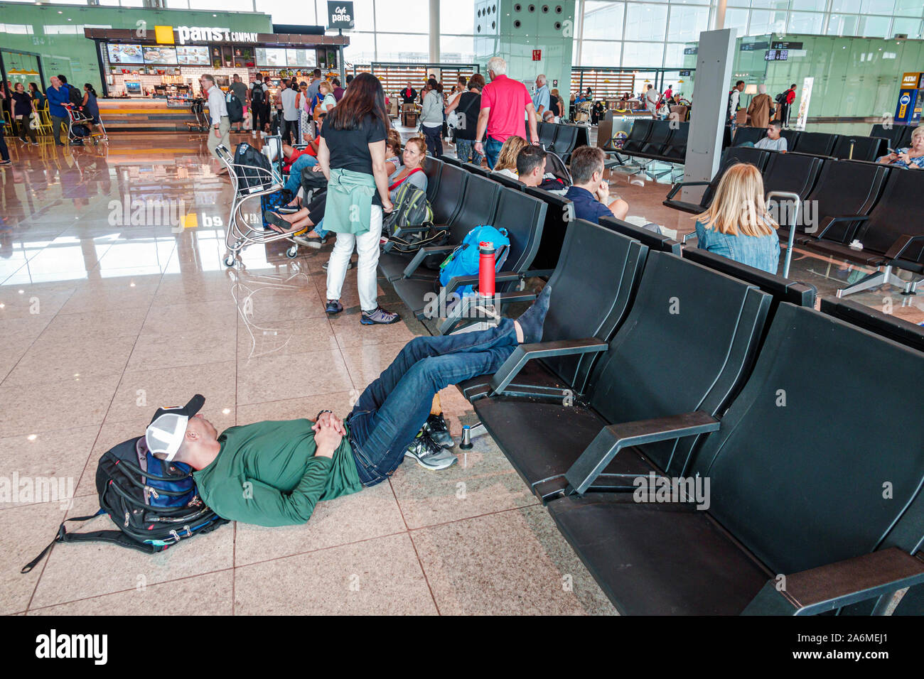 Barcelona Spain,Catalonia Barcelona-El Prat Josep Tarradellas Airport BCN,terminal T1,A,passengers,waiting area seating,man,taking nap sleeping restin Stock Photo