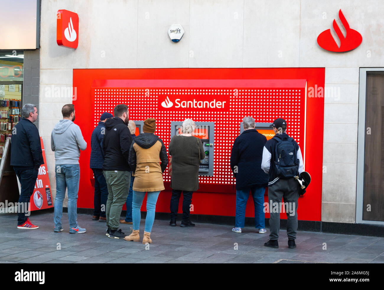 People lining up to use cash machines at a Santander bank in Liverpool Stock Photo
