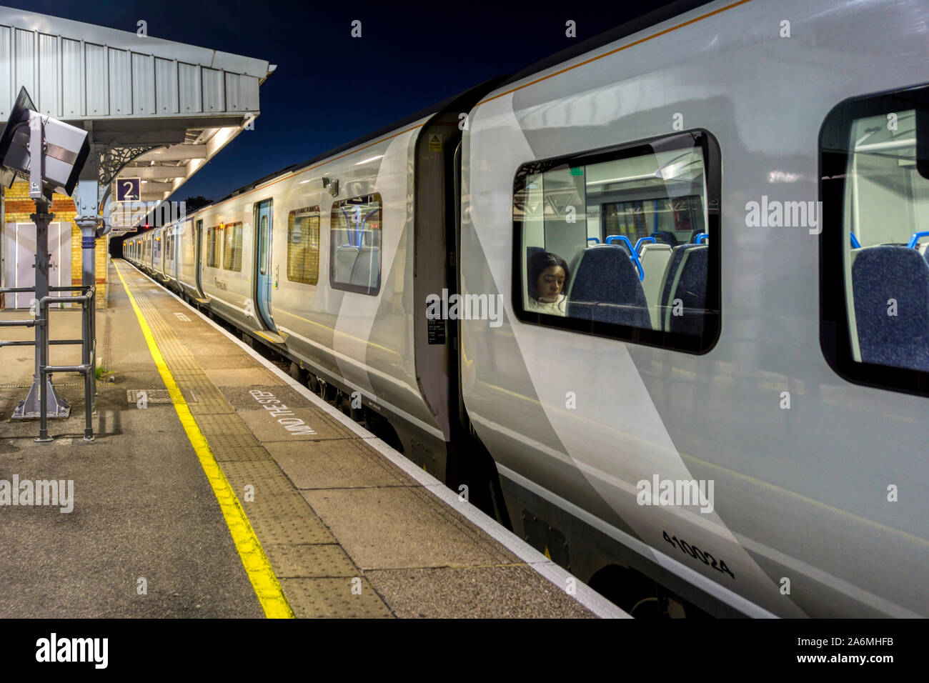A ThamesLink train stopped at a deserted London suburban station platform at night. Stock Photo
