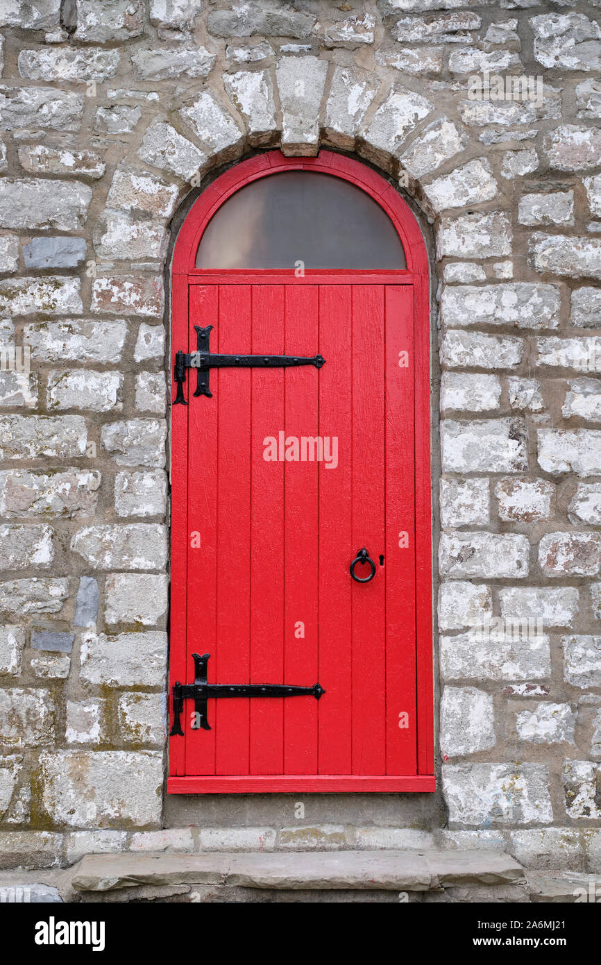 The bright red door with black iron hardware is the entrance to the old stone Gibraltor Point lighthouse on Toronto Island. Stock Photo