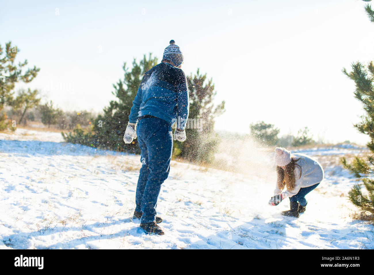 Loving couple play snowballs in winter in the forest. Throw each other ...