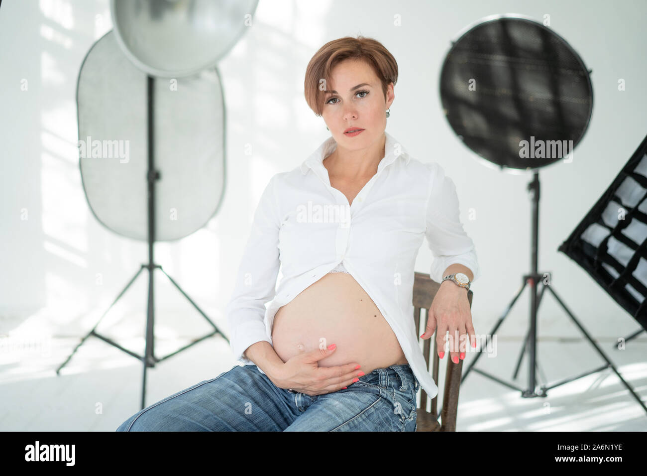 Middle-aged Pregnant Woman Sits On A Chair In The Middle Of A Photo Studio Stock Photo