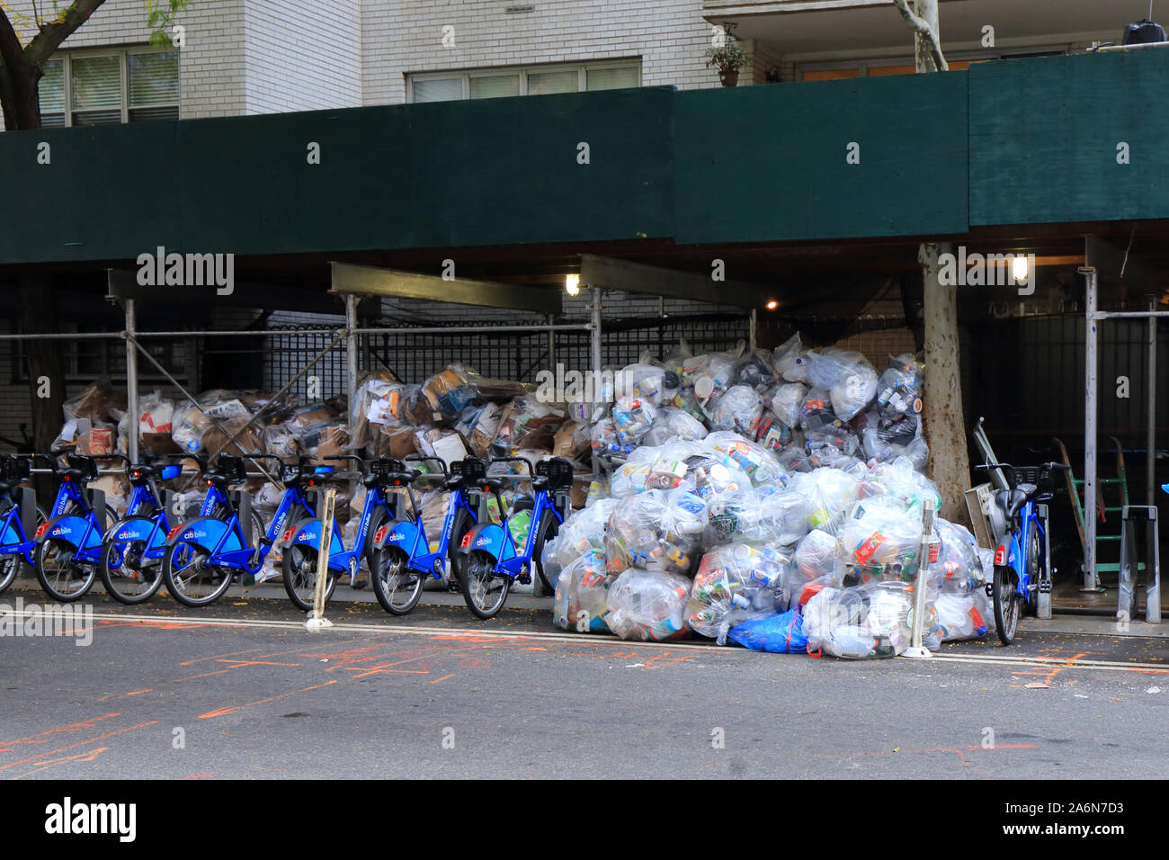 An organized trifecta of garbage, sidewalk scaffolding, and citibikes in New York City Stock Photo