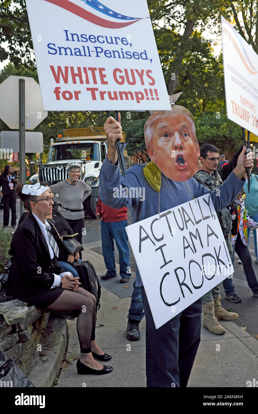 Person wears a Trump mask while wearing a sign stating 'Actually I am A Crook' signaling discontent with the President while at a protest in Ohio. Stock Photo