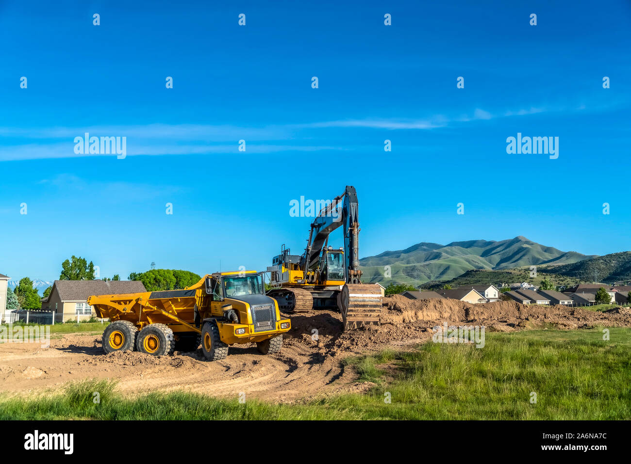 Truck and excavator at a construction site with blue sky overhead on a ...