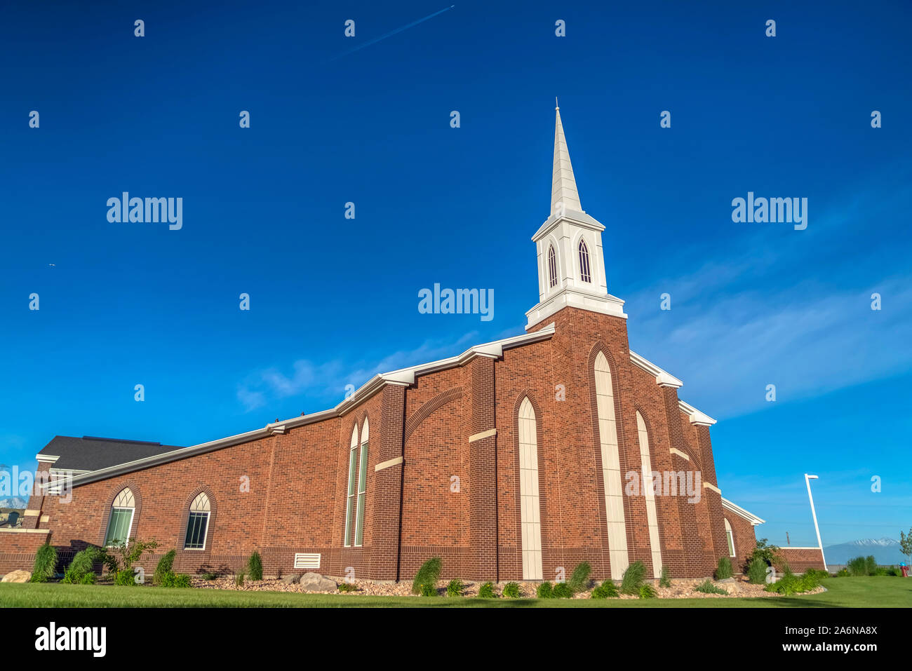 Sunny day view of a church with white steeple and vibrant blue sky ...