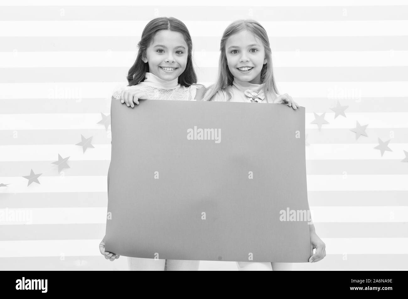 For your text. Happy children holding empty sheet of paper. Little children smiling with pink drawing paper. Small children with blank advertisement poster. Cute children advertising, copy space. Stock Photo