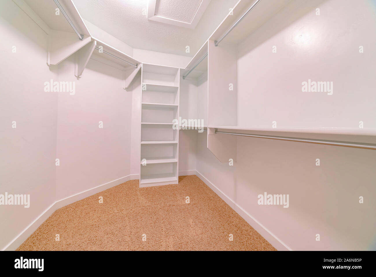 Empty walk in closet interior of a new house with shelves rods and ...