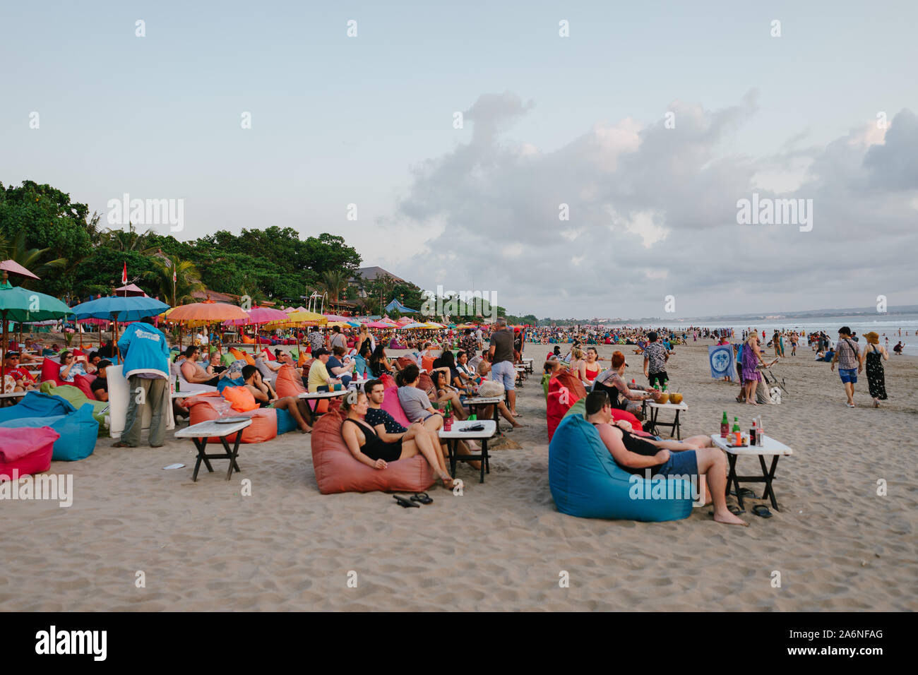 Tourists laying on colorful bean bags to see sunset from Seminyak beach