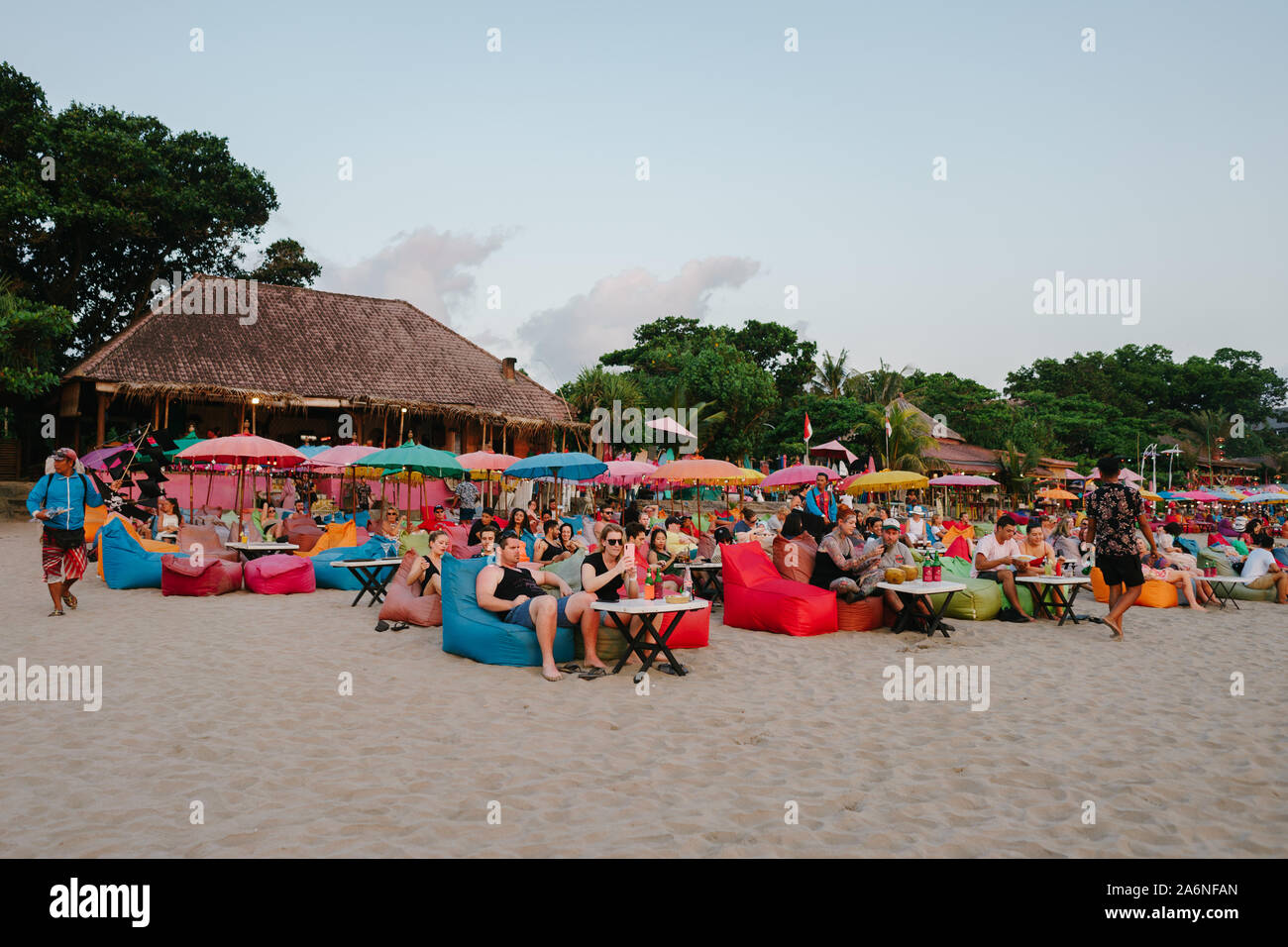 Tourists laying on colorful bean bags to see sunset from Seminyak beach