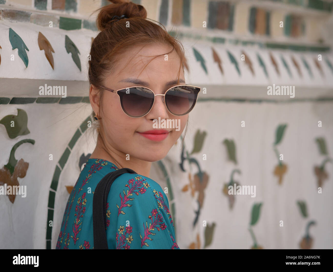Young beautiful Vietnamese woman with modern sunglasses poses for the camera at Bangkok’s Wat Arun temple. Stock Photo