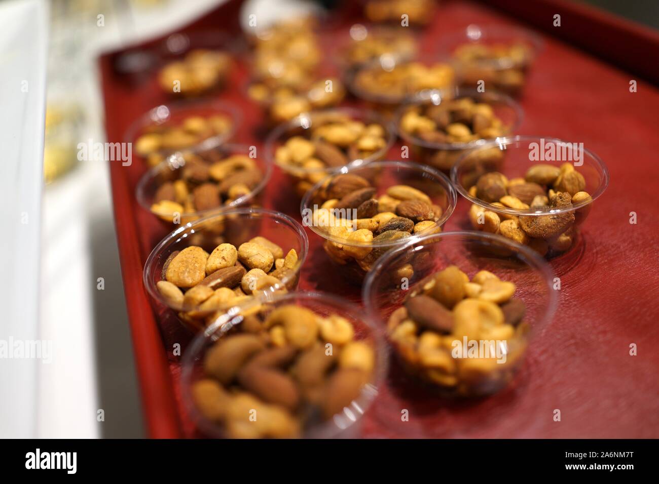 a redcolored wood tray with an arrangement of small glass bowls holding an assortment of nuts