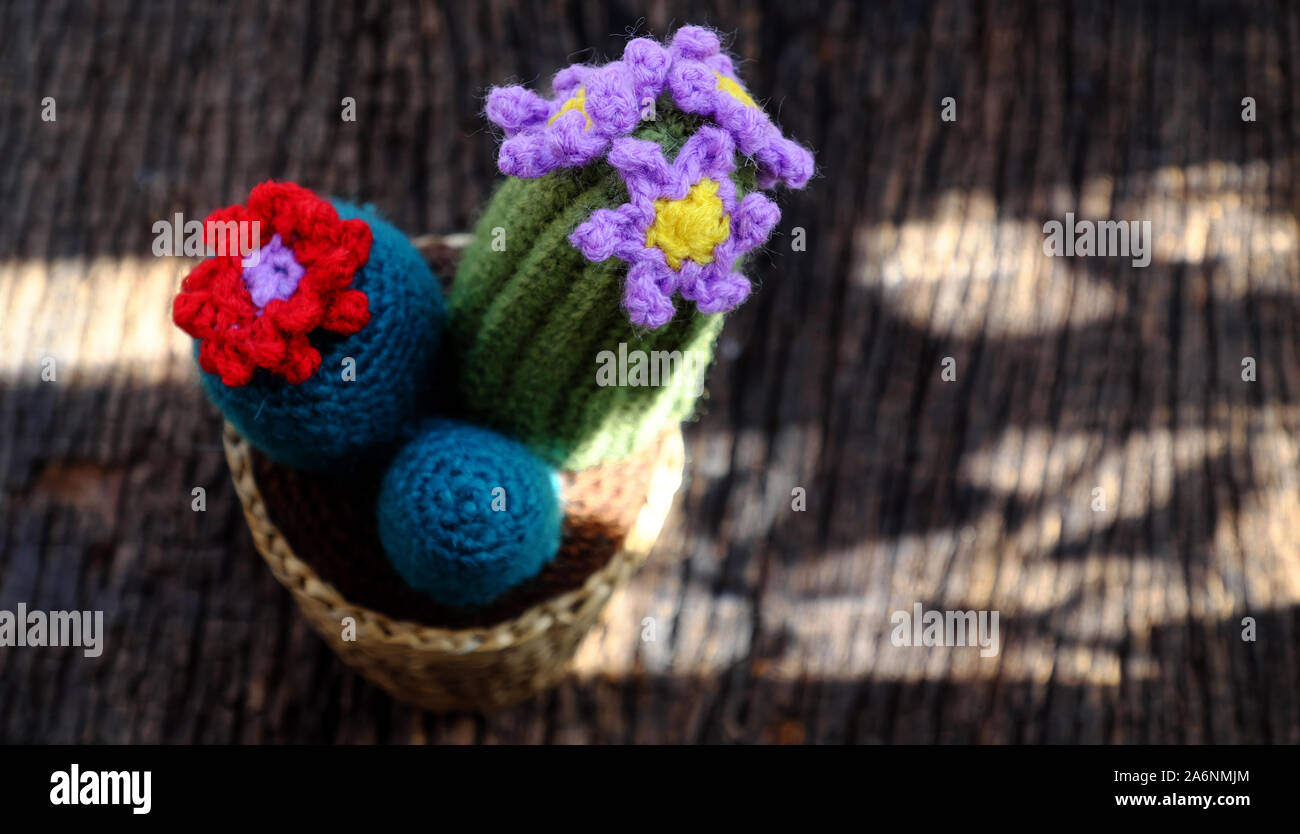 Beautiful handmade product for decorate, cacti and cactus flower crochet from green yarn, ornament plant pot on outdoor table in morning sunlight Stock Photo