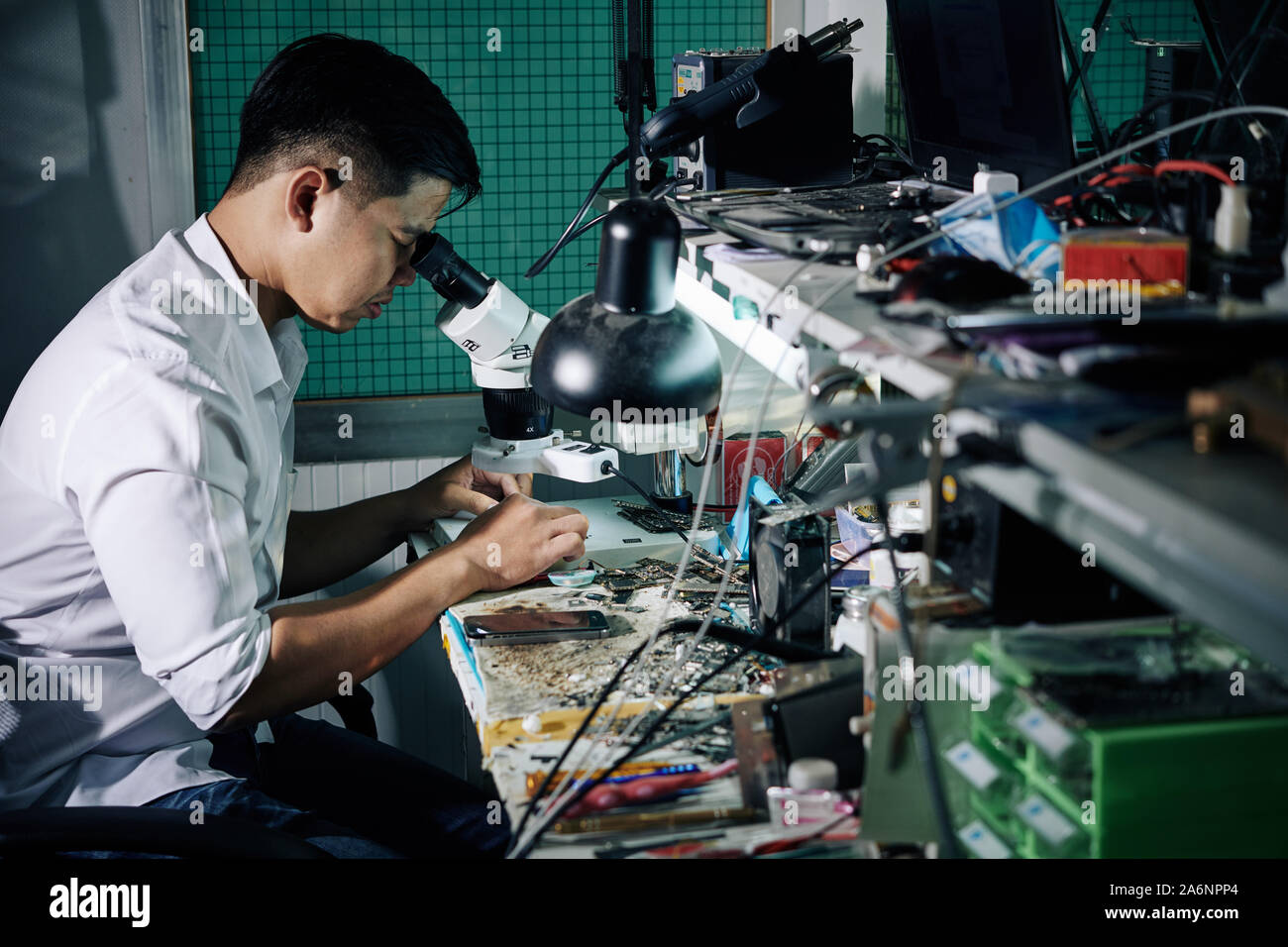 Repairman using microscope when fixing small details in smartphone Stock Photo