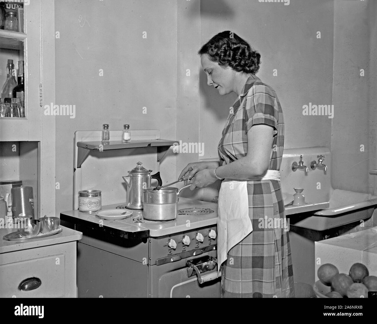 A woman cooking on a stove in the kitchen in 1937 Stock Photo
