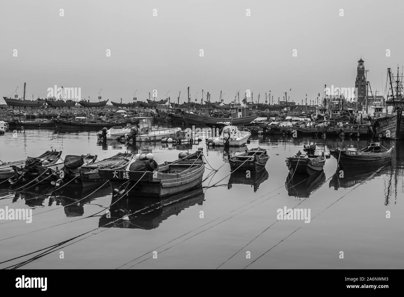 Black and white picture of boats in Dalian old harbor, in China during cloudy weather (Dalian in Chinese) Stock Photo