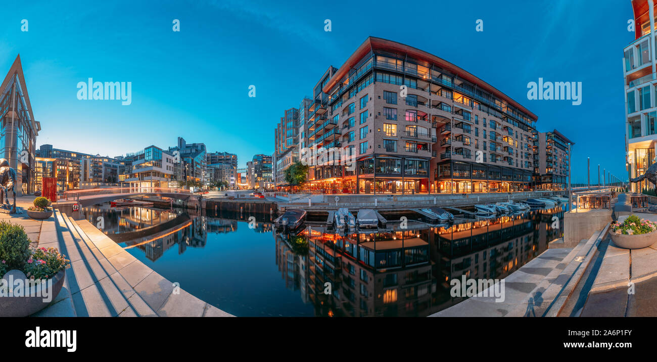 Oslo, Norway - June 24, 2019: Night Embankment And Residential Multi-storey Houses In Aker Brygge District. Summer Evening. Residential Area Reflected Stock Photo