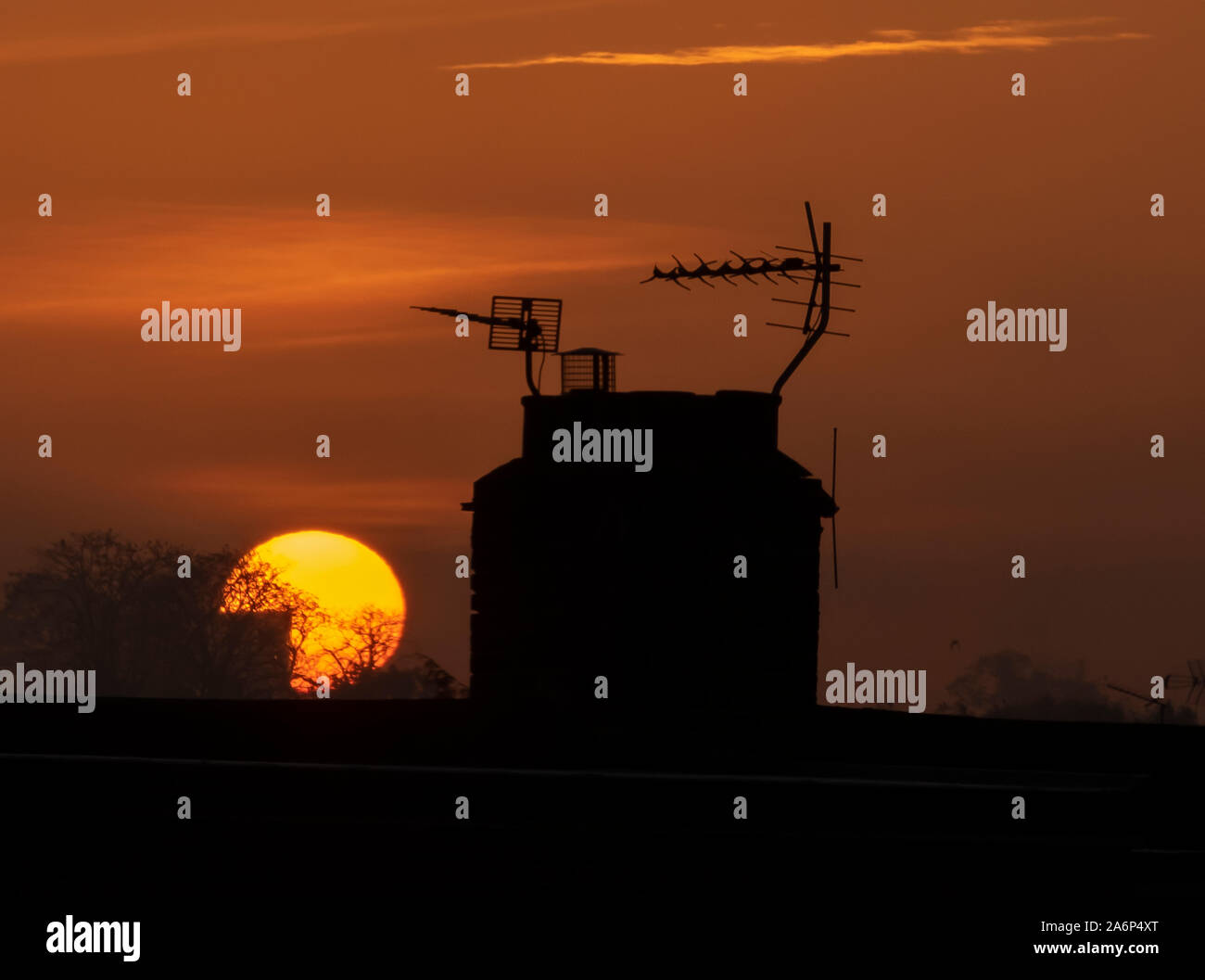 Wimbledon, London, UK. 28th October 2019. Orange sunrise in clear sky behind rooftops in south London after the first local Autumn night frost of 2019. Credit: Malcolm Park/Alamy Live News. Stock Photo