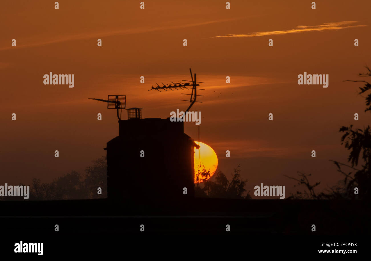 Wimbledon, London, UK. 28th October 2019. Orange sunrise in clear sky behind rooftops in south London after the first local Autumn night frost of 2019. Credit: Malcolm Park/Alamy Live News. Stock Photo