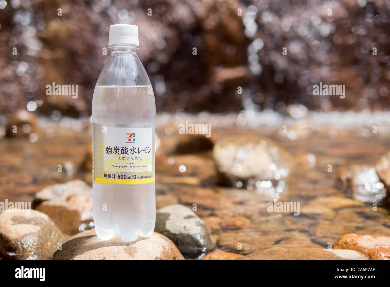 Seven Eleven sparkling water on brown rocks, blurred background in