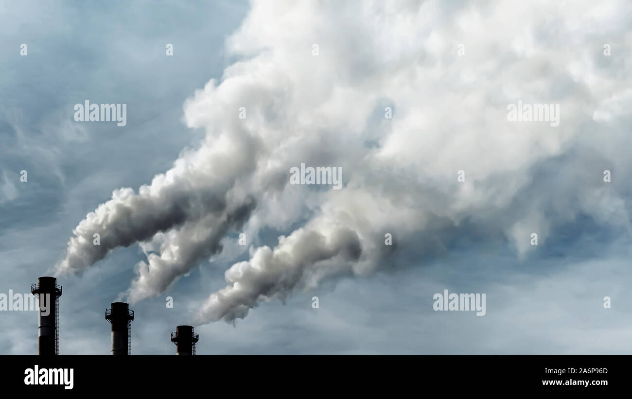 Toxic emissions of toxic gases into the atmosphere, industrial air pollution. Dark chimneys blowing huge billows of smoke into the sky Stock Photo