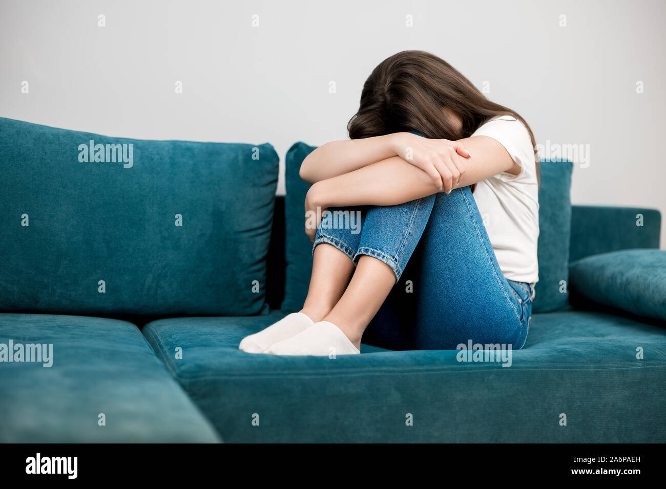 young woman crying feeling very depressed sitting on the sofa with her head down tough life Stock Photo