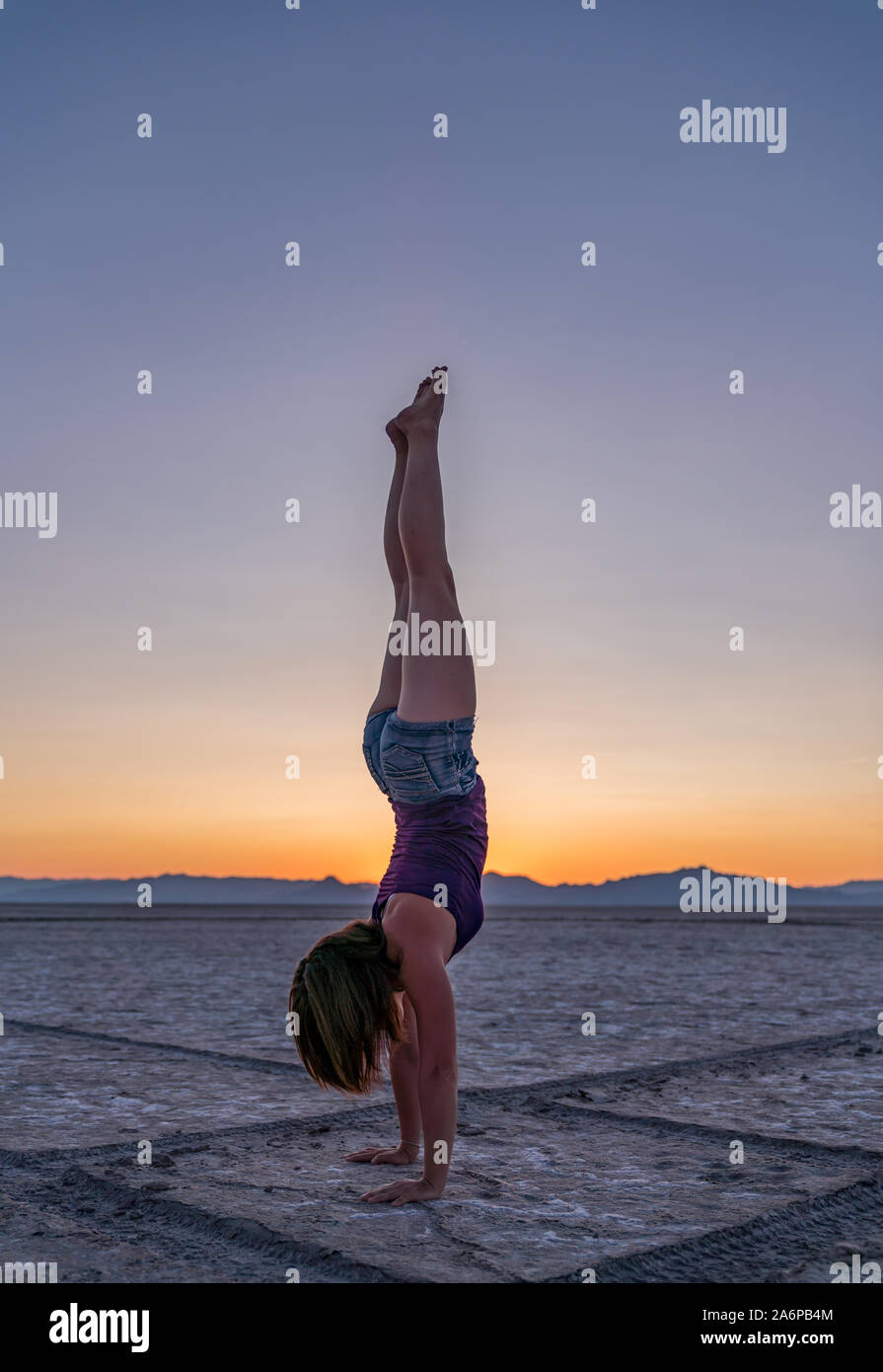Beautiful Woman Doing Handstands During Sunset in Bonneville Salt flats Stock Photo