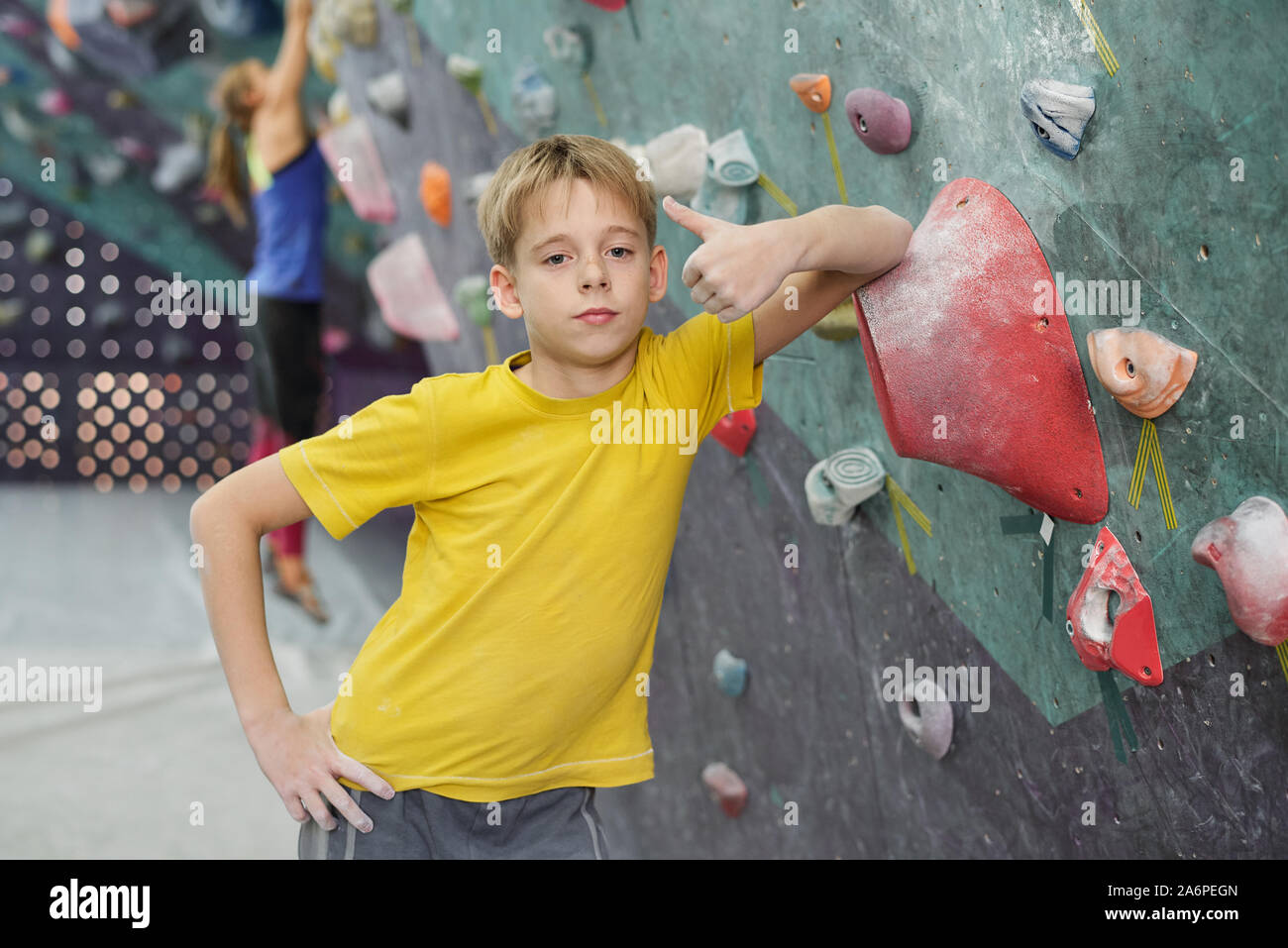 Cute boy showing thumb up while leaning by rock climbing equipment Stock Photo