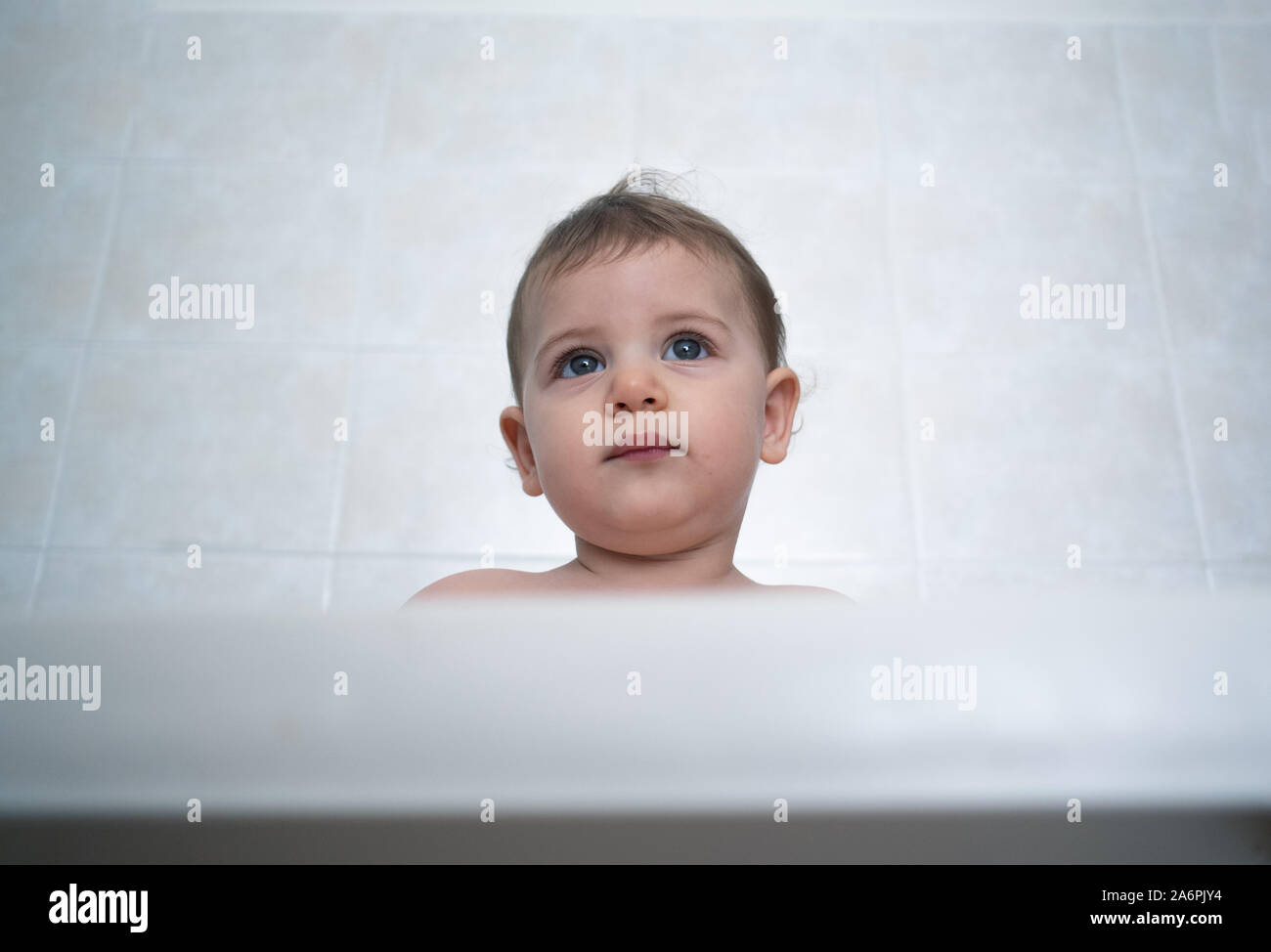 1 year old female baby sits in a high chair waiting for her meal Stock Photo