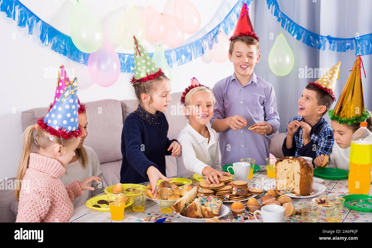 Cheerful teenagers having dinner to celebrate friend’s birthday Stock