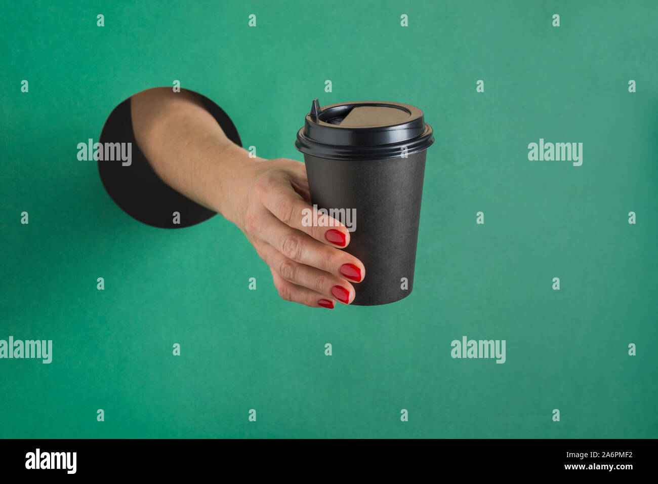 Female hand holding disposable paper black coffee cup through round ...