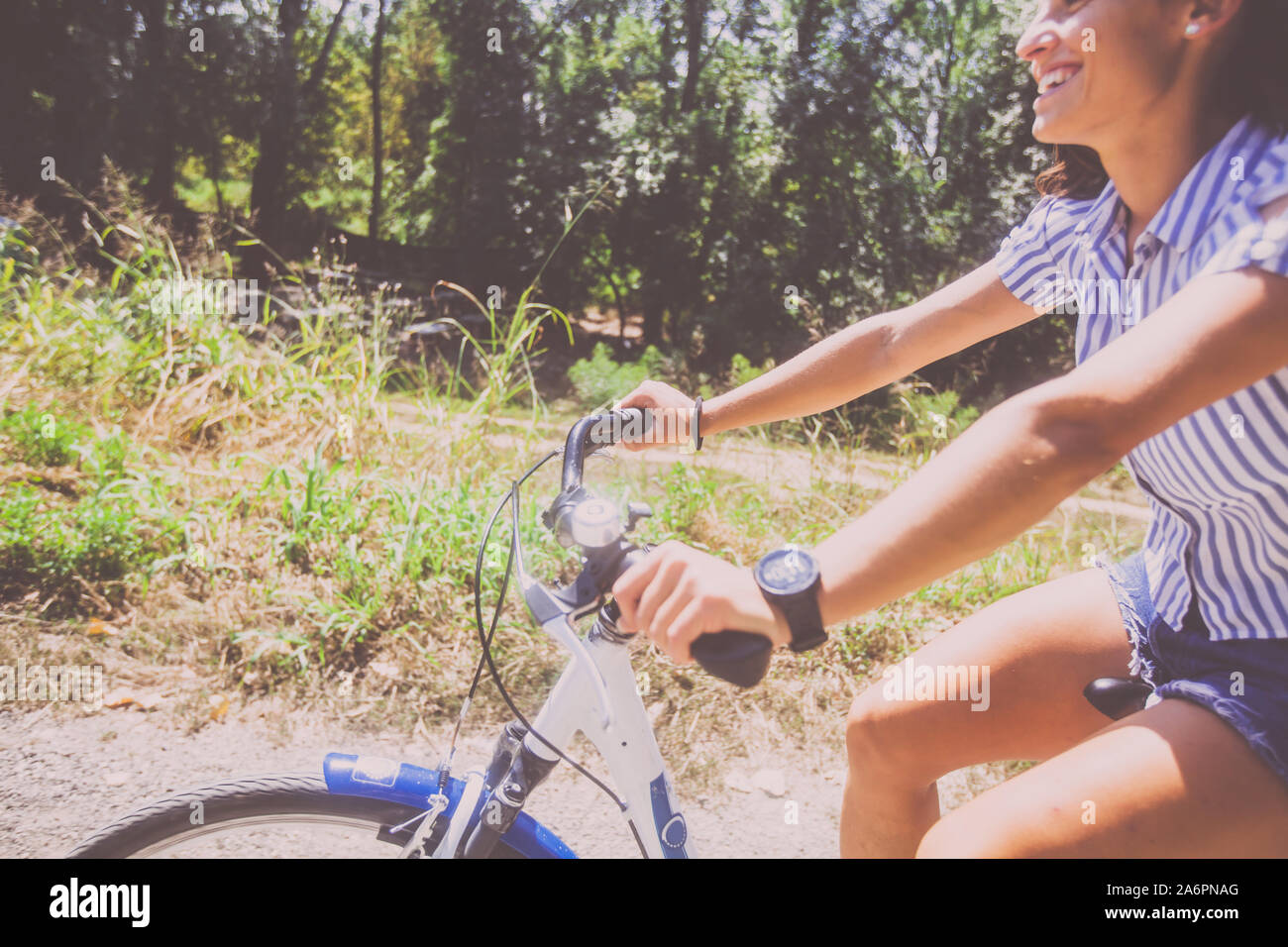 Closeup view of attractive woman in jeans shorts riding bicycle in the ...