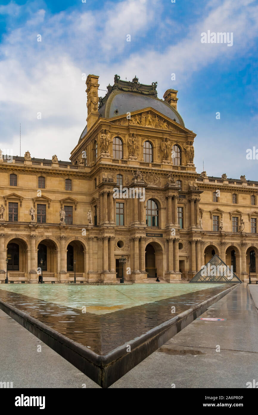 Great portrait view of the lovely façade of the Louvre's Denon Wing, a small glass pyramid and the corner of the water basin pointing directly to the... Stock Photo