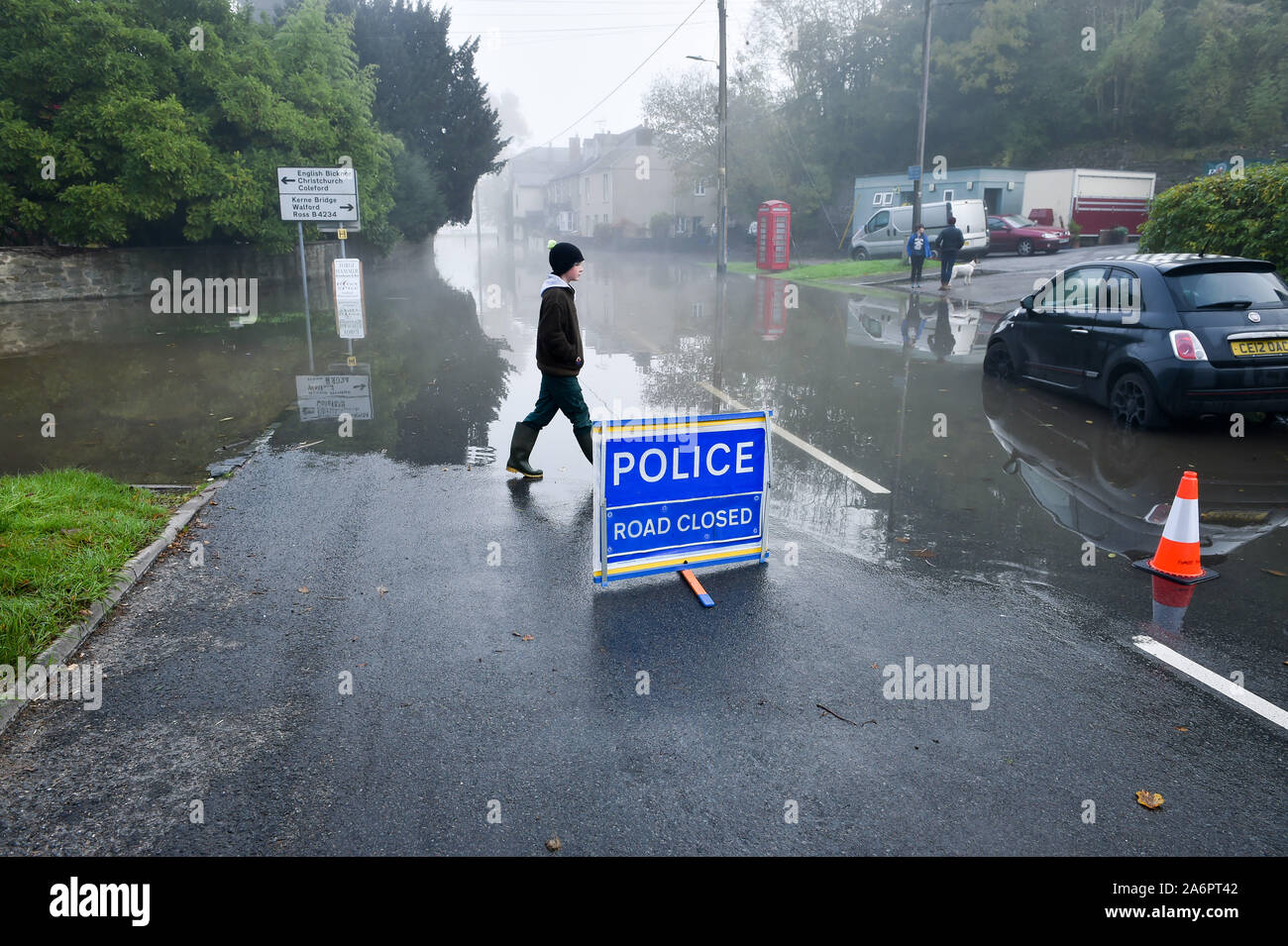 A person walks past a police road closure sign in Lower Lydbrook, where rain from the Welsh hills and high tides have flooded the village, which sits next to the banks of the River Wye, rendering it impassable. Stock Photo