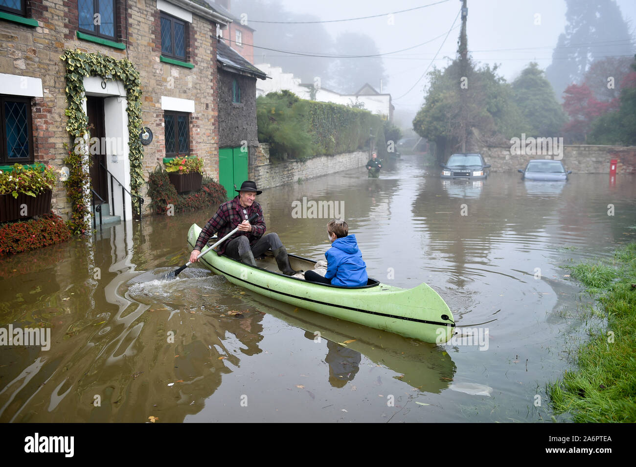 Paul Hayes ferries children to dry land after their family holiday accommodation has been surrounded by floodwater in Lower Lydbrook, where rain from the Welsh hills and high tides have flooded the village, which sits next to the banks of the River Wye, rendering it impassable. Stock Photo