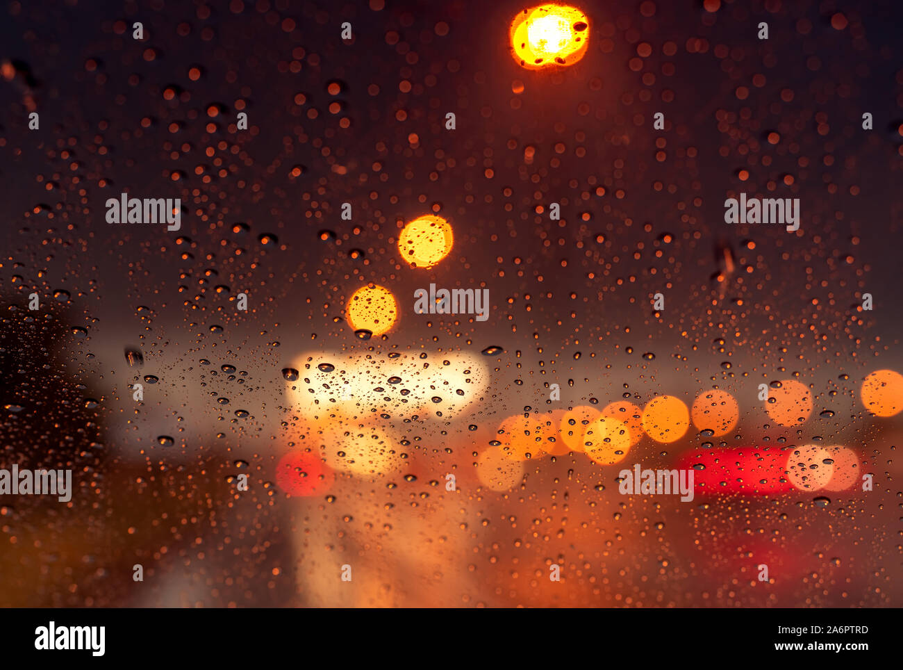 Orange night light bokeh from street light on traffic jam day. Rainy day. Transparent glass window with rain drop. Romantic weather. City life. Blur Stock Photo