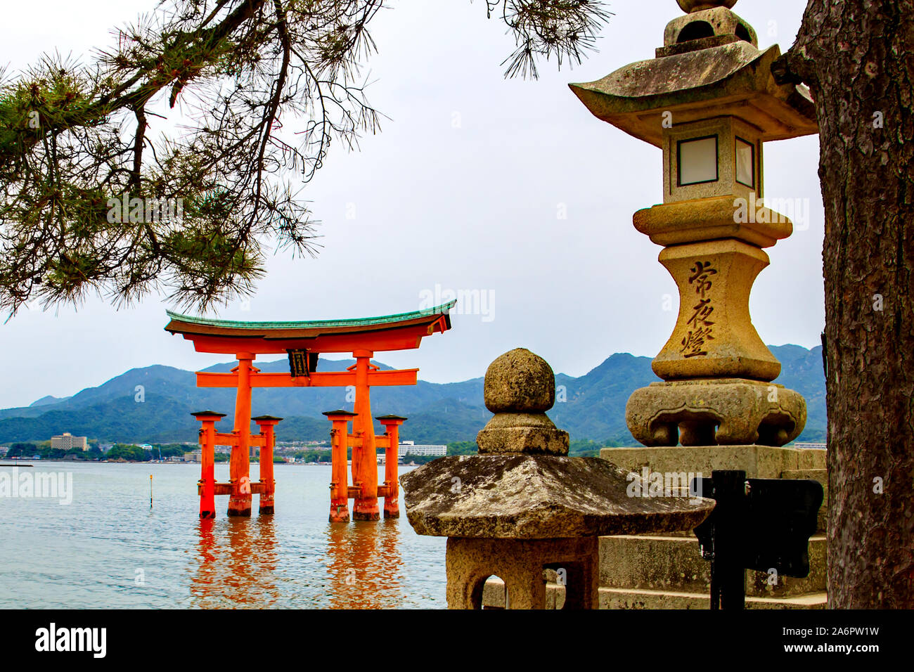 Japanese stone lanterns with the floating torii gate of Itsukushima Shrine in the sea off Miyajima Island, Japan Stock Photo